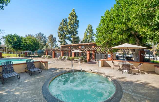 a pool with a hot tub and a patio with tables and chairs