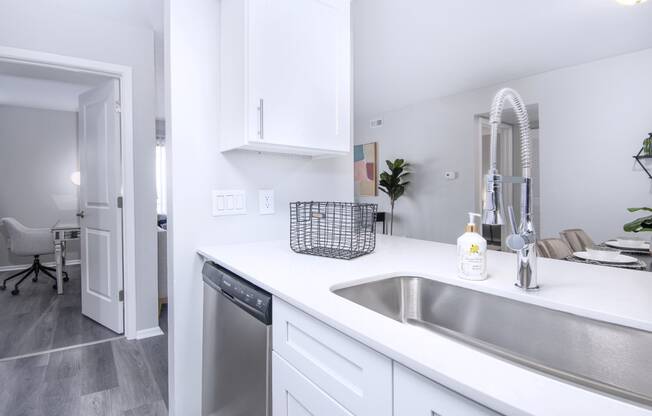 a kitchen with a sink and a dishwasher and a door to a living room