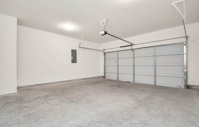 A large empty garage with a white door and a grey floor.