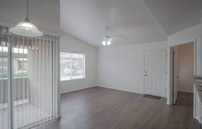 an empty living room with a white door and a ceiling fan