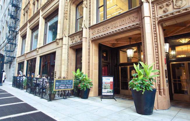 the outside of a building with potted plants on the sidewalk