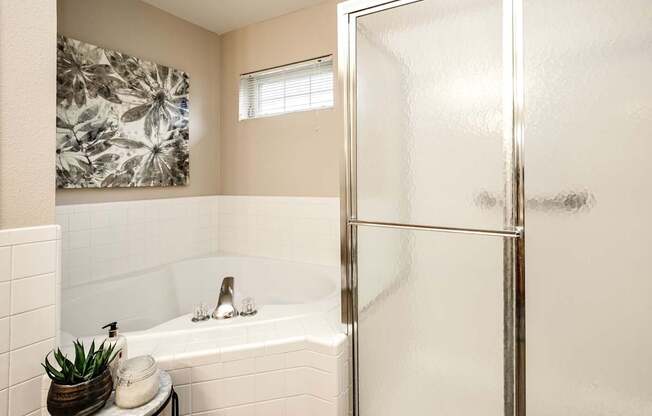 A bathroom with a white tub and a glass shower door. at Tranquility Pointe, Nebraska