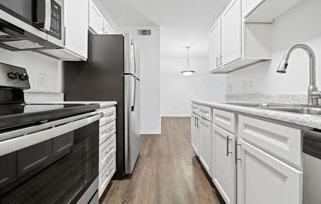 A modern kitchen with white cabinets and stainless steel appliances.