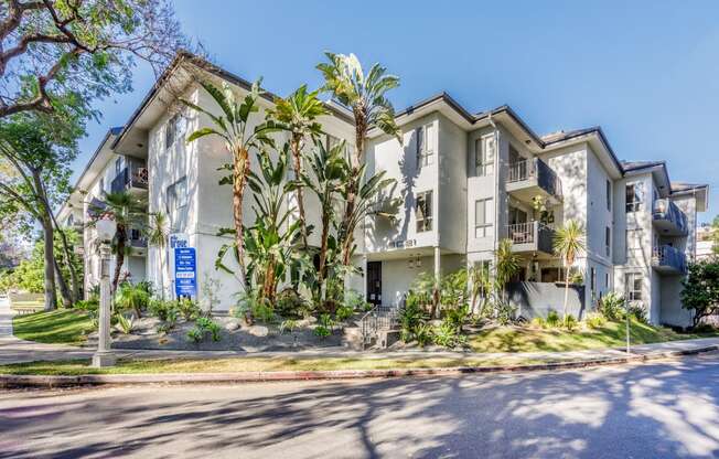 a large apartment building with palm trees in front of it