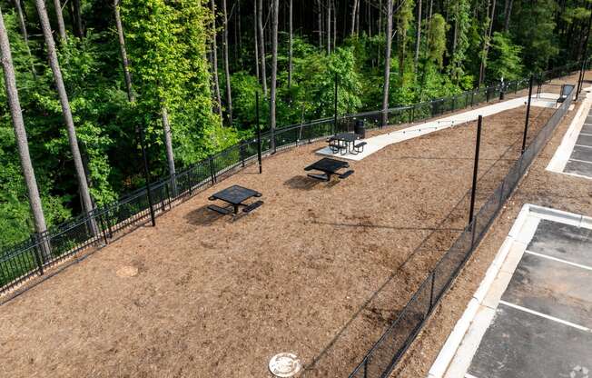 a fenced in dog park with benches and trees at Preston Ridge Apartments Cary, NC