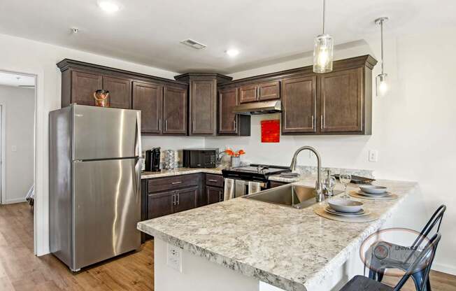 A kitchen with quartz counter tops, dark cabinets, and stainless steel appliances.