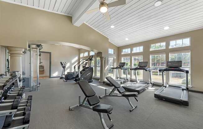 A spacious gym with a variety of equipment including treadmills, weights, and a bench.