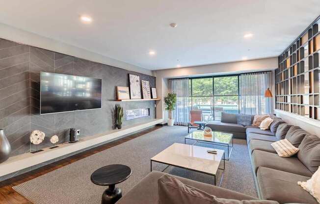 A modern living room with a grey couch, a black coffee table, and a flat screen TV mounted on the wall.