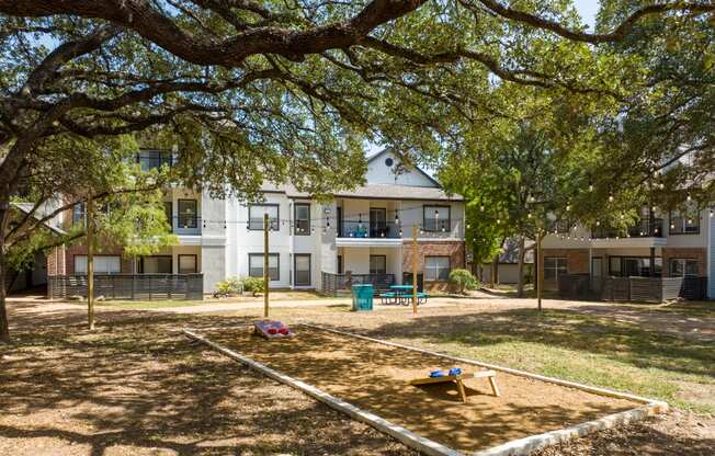 a park with a sandbox and a picnic table in front of an apartment building