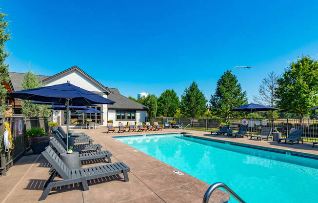 our resort style swimming pool with lounge chairs and umbrellas