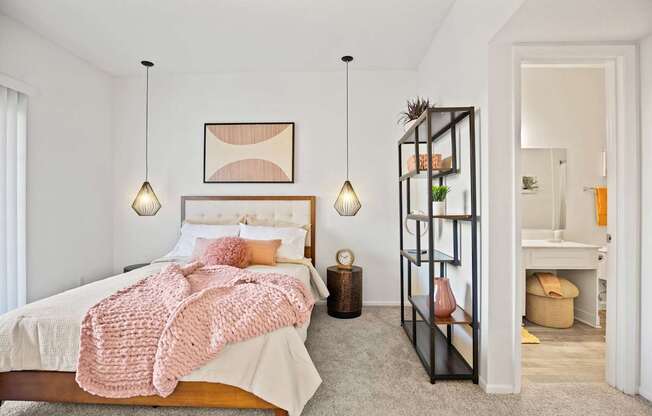 A bedroom with a bed, a shelf, and a lamp.