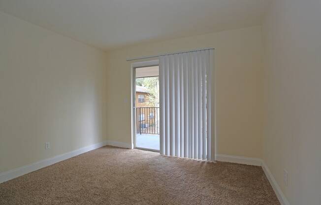 A room with a carpeted floor and a sliding glass door.