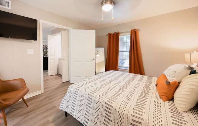 A bedroom with a bed, chair, and a television.