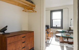 a living room with a dresser and a door into a room