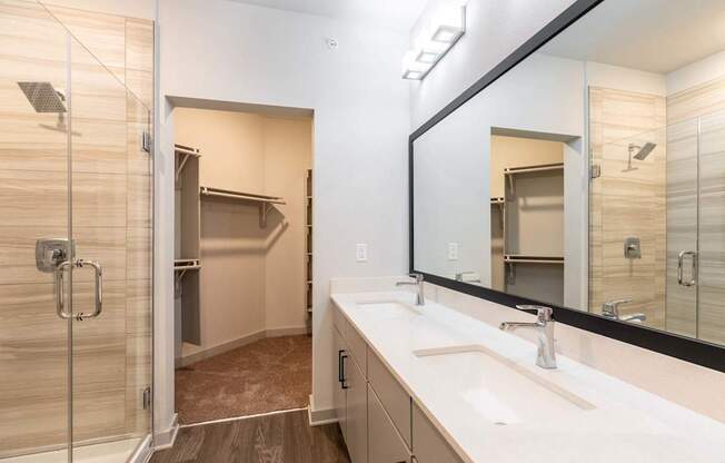 A bathroom with a walk-in shower, double sinks, and a large mirror.