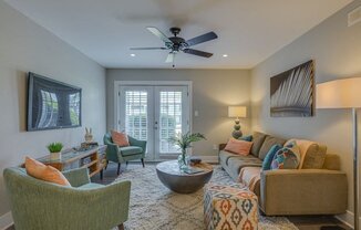 a living room with a couch and chairs and a ceiling fan