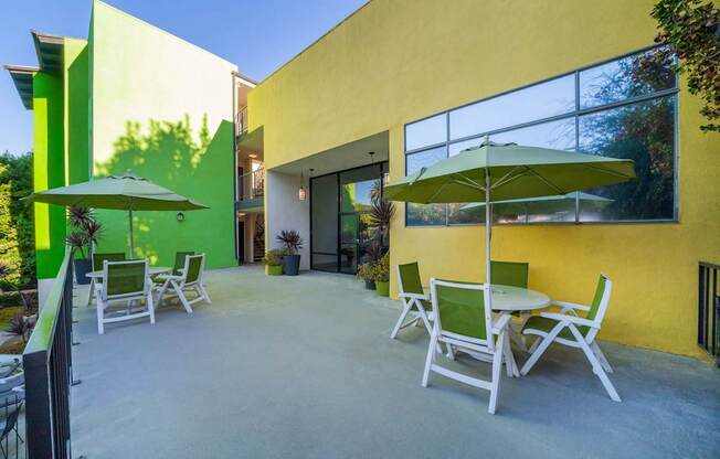 A patio with a table and chairs and a green umbrella.