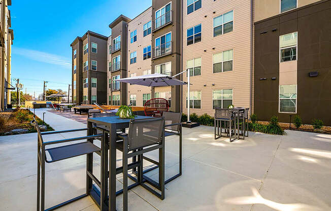 a patio with a table and chairs in front of an apartment building at Mockingbird Flats, Dallas, 75206