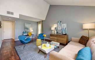 Model home with vaulted ceilings, hardwood inspired flooring and blue accents with the chairs and couch pillows.