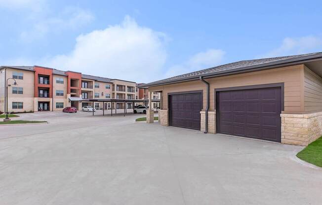 A parking lot in front of a building with a red car parked in the lot.