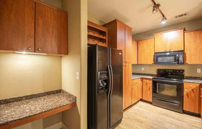 a kitchen with wood cabinets and black appliances At Metropolitan Apartments in Little Rock, AR