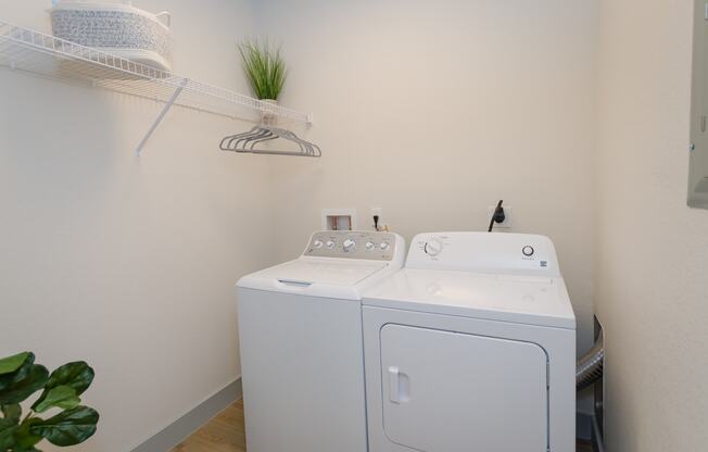 a white washer and dryer in a white room with a shelf above it at Lofts at South Lake, Clermont, FL, 34711