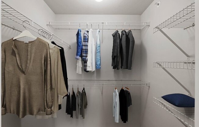 a walk in closet with a white closet and white shelves