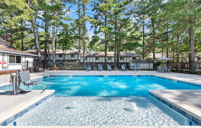 A large swimming pool surrounded by trees and chairs.