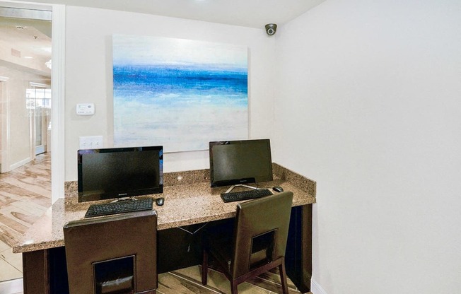 a computer desk with two monitors and two chairs