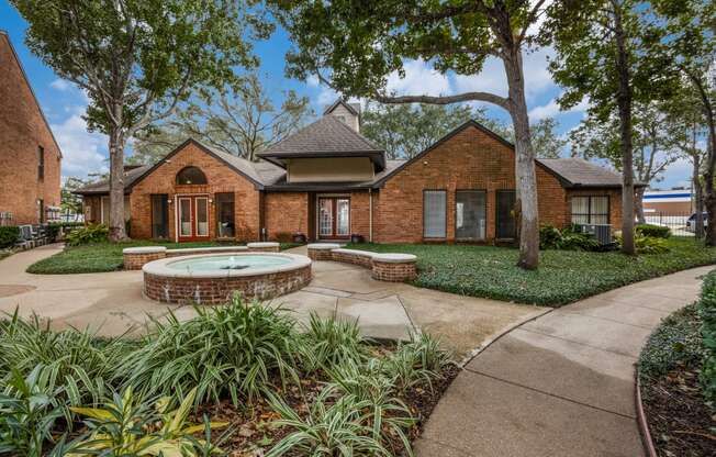 a walkway leading to a brick house with a fountain