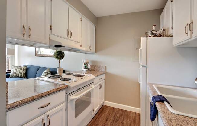 Full Kitchen with 2 door refrigerator, electric range over range hood, double kitchen sink, granite countertops, white kitchen cabinets, wood-inspired floors