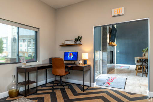 an office area with a desk with a computer and a window