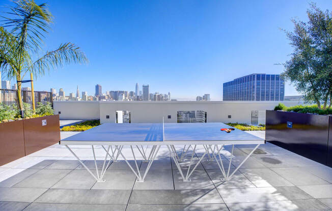 a ping pong table on the roof of a building with a cityscape in the background