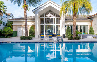 a swimming pool in front of a house with palm trees