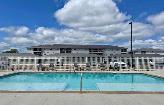 A swimming pool in front of a building with a cloudy sky.