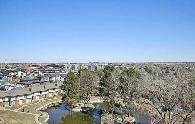A view of a residential area with a pond and trees.