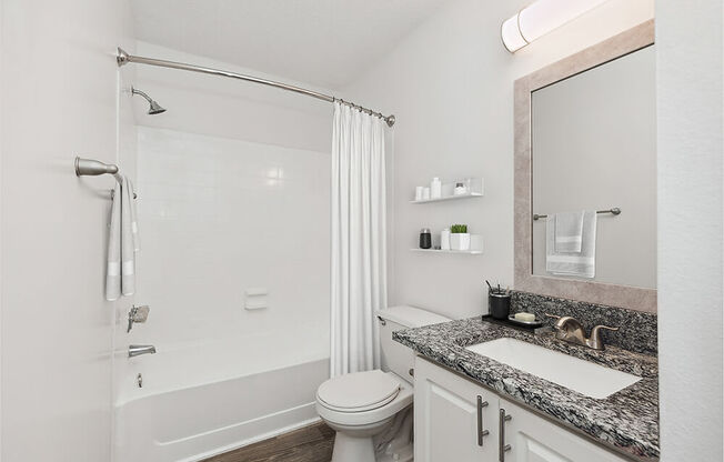 Model Bathroom with White Cabinets and Wood-Style Flooring at Seven Lakes at Carrollwood Apartments in Tampa, FL.