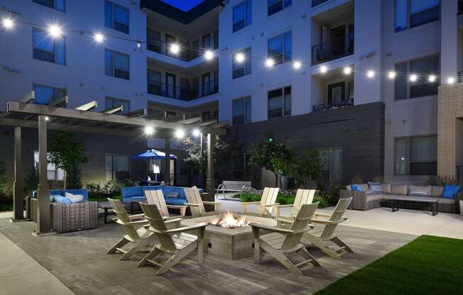 a patio with chairs and a fire pit at night