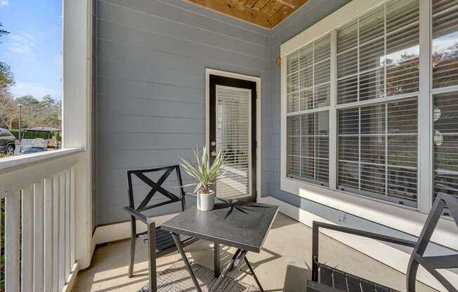 A small table with a potted plant on it is on a porch.