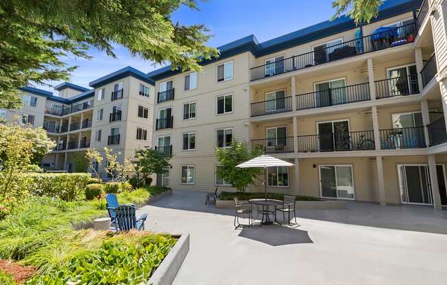 a patio with a table and chairs in front of the property building at Guinevere Apartment Homes, WA 98103