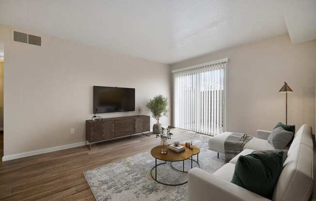 an apartment living room with a couch and a tv with private outdoor patio access.