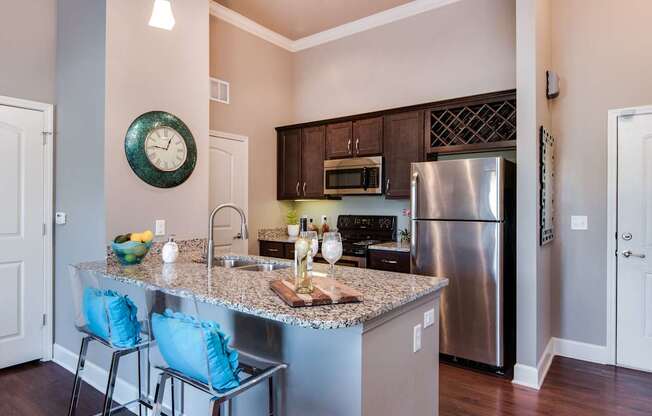 A kitchen with a granite countertop and a stainless steel refrigerator.