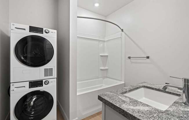 A modern laundry room with a washer and dryer stacked on top of each other. at Brickside Heights, Utah