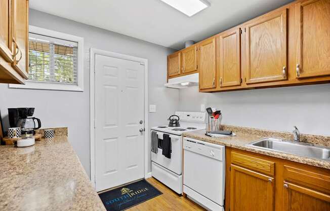 A kitchen with white appliances and wooden cabinets.