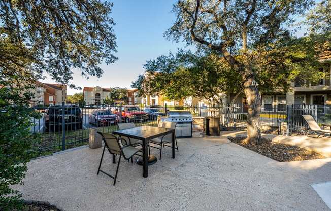 A patio with a table and chairs surrounded by trees.