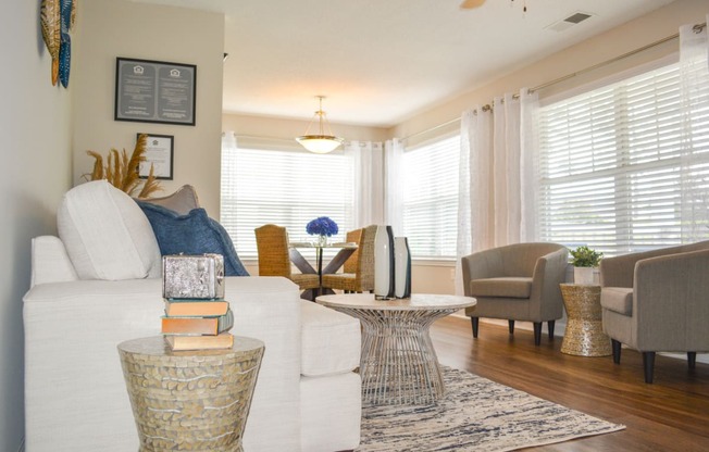 a living room with a white couch and chairs and a table