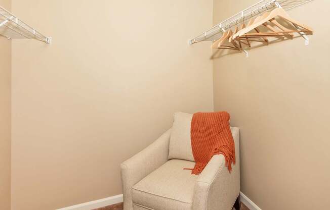 A white chair with an orange blanket draped over it in a large closet at The Landing Apartments and Townhomes, Oregon, 97045