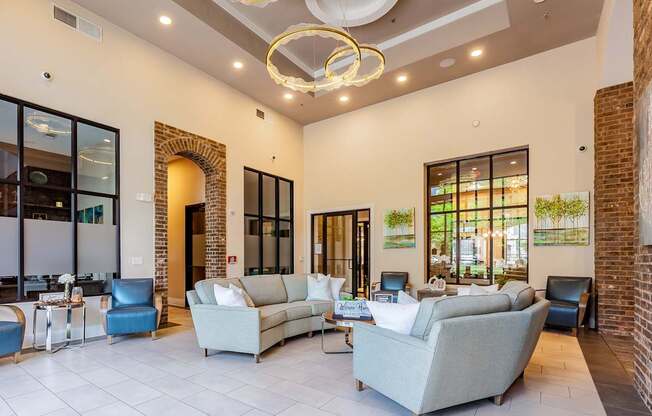 A living room with a grey couch and a chandelier.