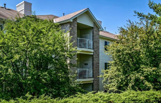 an apartment building with trees and bushes in front of it