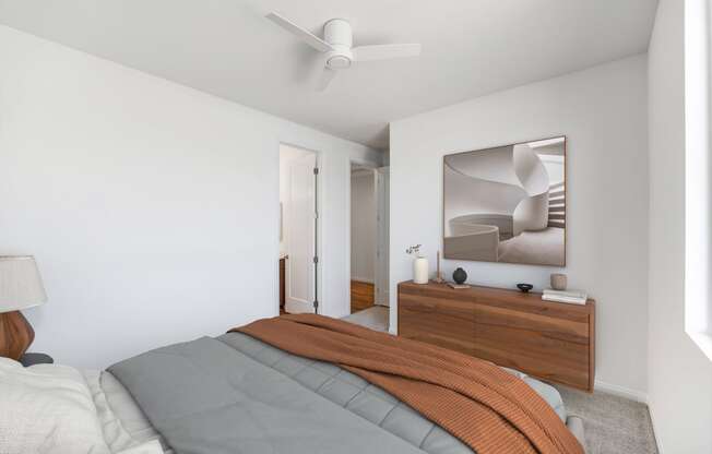 a bedroom with white walls and a bed with an orange blanket